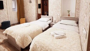Una habitación de hotel con dos camas, un espejo, una araña y papel tapiz estampado.