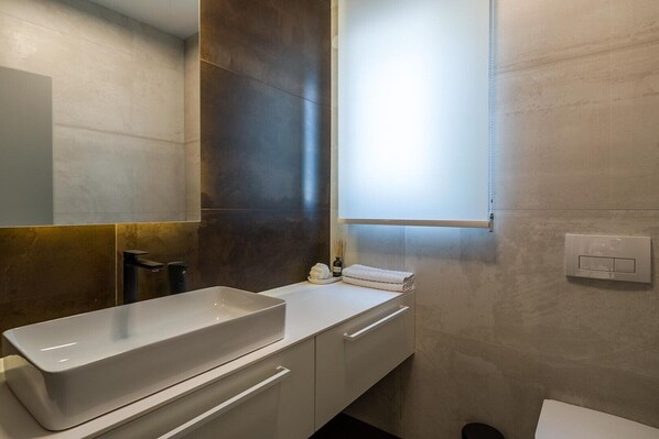 A modern bathroom with a rectangular sink, a mirror, and a window. - Villa Valinka Design (Golas)