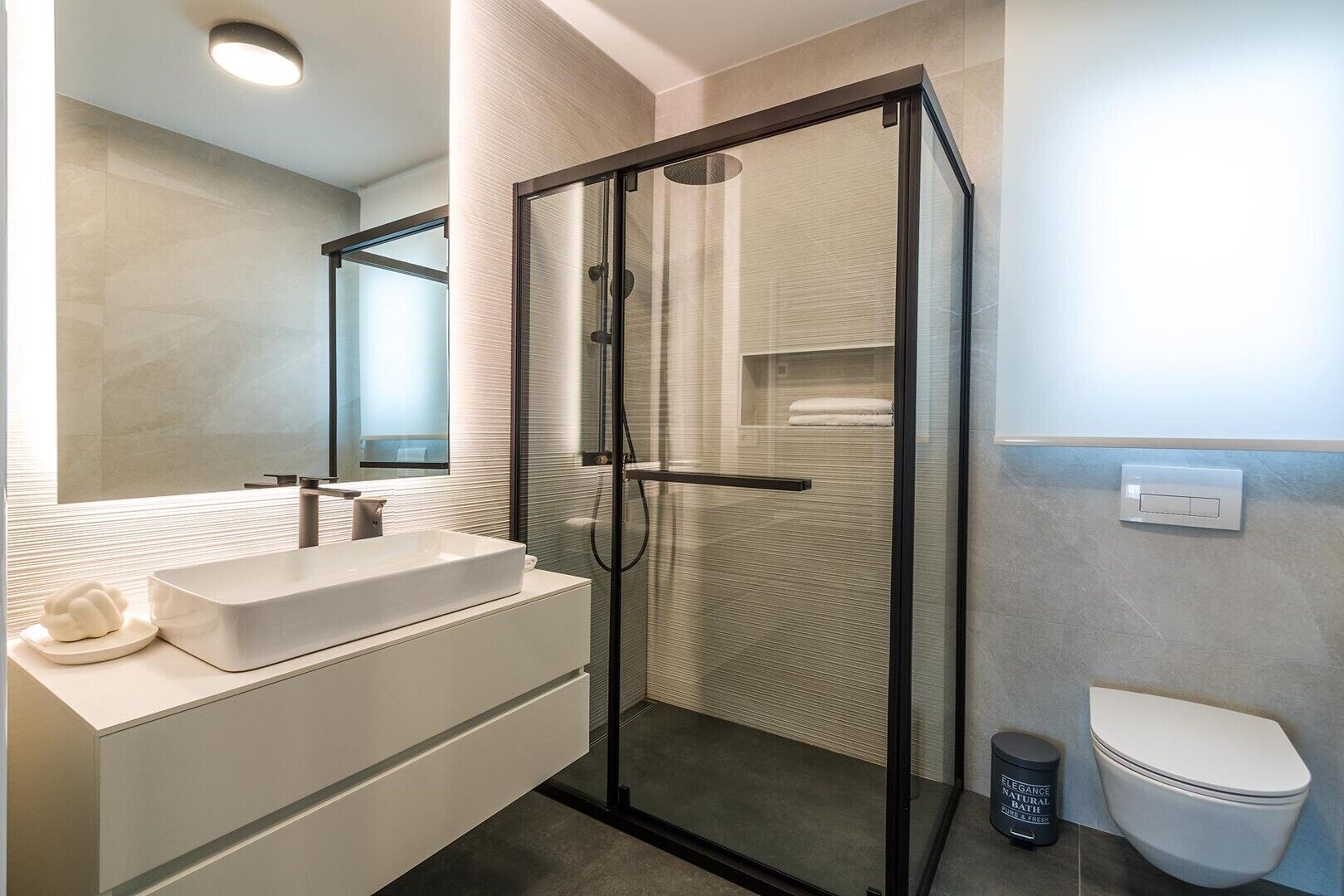 Une salle de bain moderne avec une douche à parois de verre, un lavabo blanc et des toilettes.