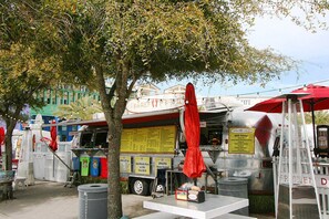 Un camión de comida con un cartel de menú y un paraguas rojo.
