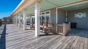 A covered outdoor deck with wooden benches and a railing, a clear blue sky, and a building with '101' on the wall.