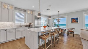 A modern kitchen with a large island, bar stools, and a view of the ocean. - Rooftop deck with Gulf views - Villa Rayo Del Sol (Bradenton Beach)