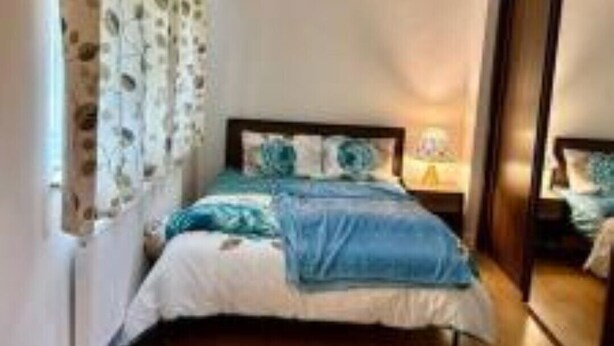 A bedroom with a bed, a nightstand, a mirror, and a door. - Spacious 3bhk Near Heathrow (Hounslow)