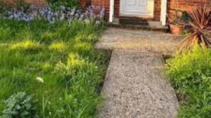 A two-story brick house with a front door, windows, and a small garden area with grass and plants. - Spacious 3bhk Near Heathrow (Hounslow)