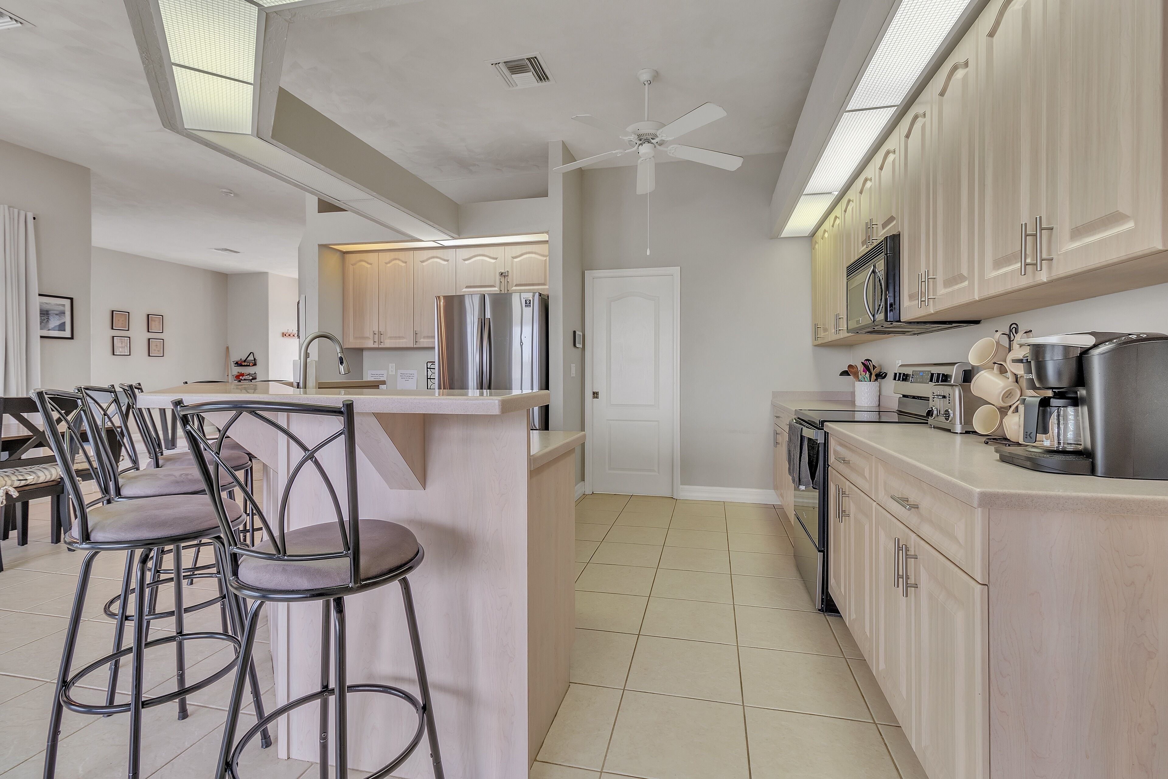 Una cocina moderna con una isla central, taburetes de bar y un ventilador de techo.