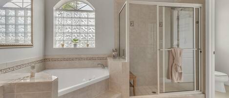 Un baño moderno con una bañera independiente, ducha con mampara de vidrio y tocador con espejo.