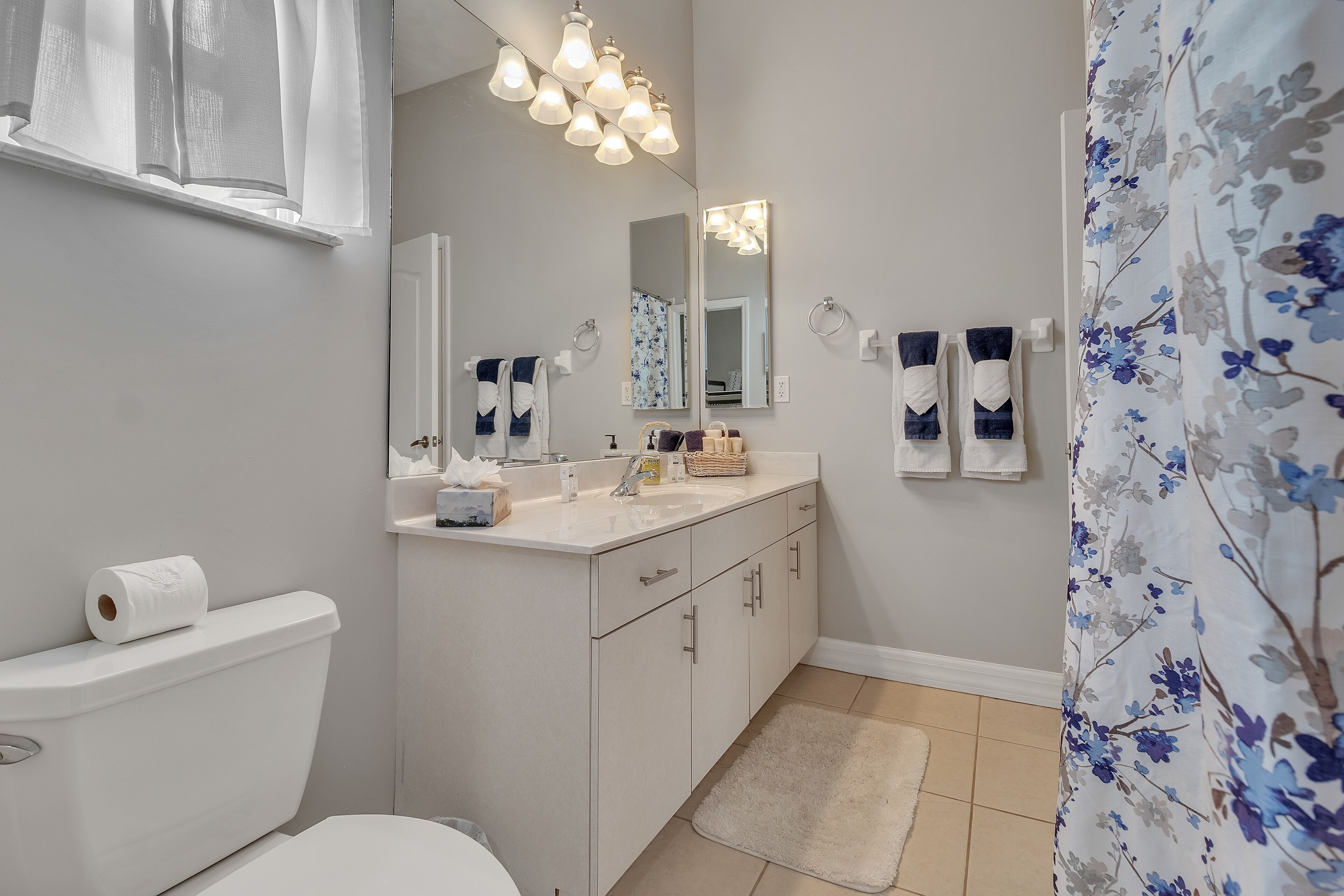 A bathroom with a toilet, sink, mirror, and shower curtain.