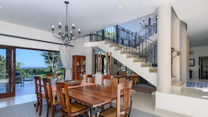A spacious dining area with a large wooden table and chairs, a chandelier, and a staircase leading to an upper level. - San Lameer Villa 14214 (Southbroom)