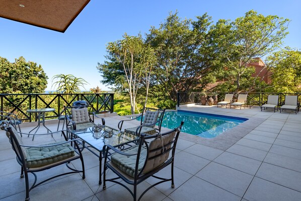 An outdoor patio with a pool, surrounded by trees and a fence. - San Lameer Villa 14214 (Southbroom)