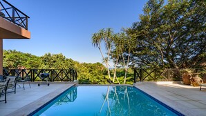 A rectangular swimming pool with clear blue water, surrounded by a deck with outdoor furniture. - San Lameer Villa 14214 (Southbroom)