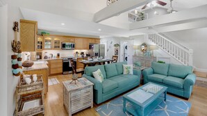 Un salon spacieux avec un canapé turquoise, une table basse et un coin repas doté de meubles en bois et d’un four à micro-ondes.