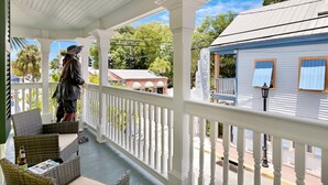 Une véranda avec des meubles en osier et une statue.
