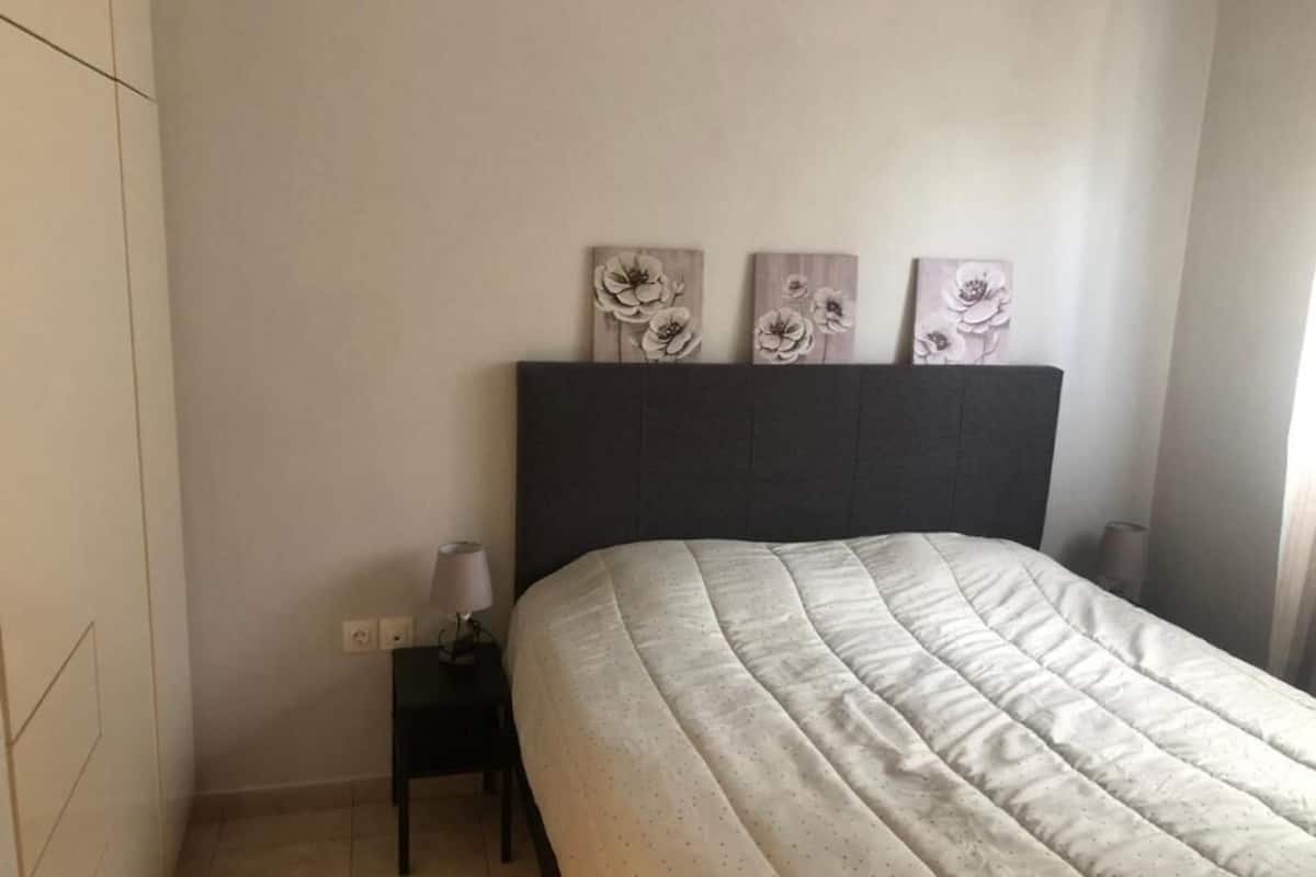 Ein Schlafzimmer mit einem Bett, einem Nachttisch und drei an der Wand befestigten Blumenbildern.
