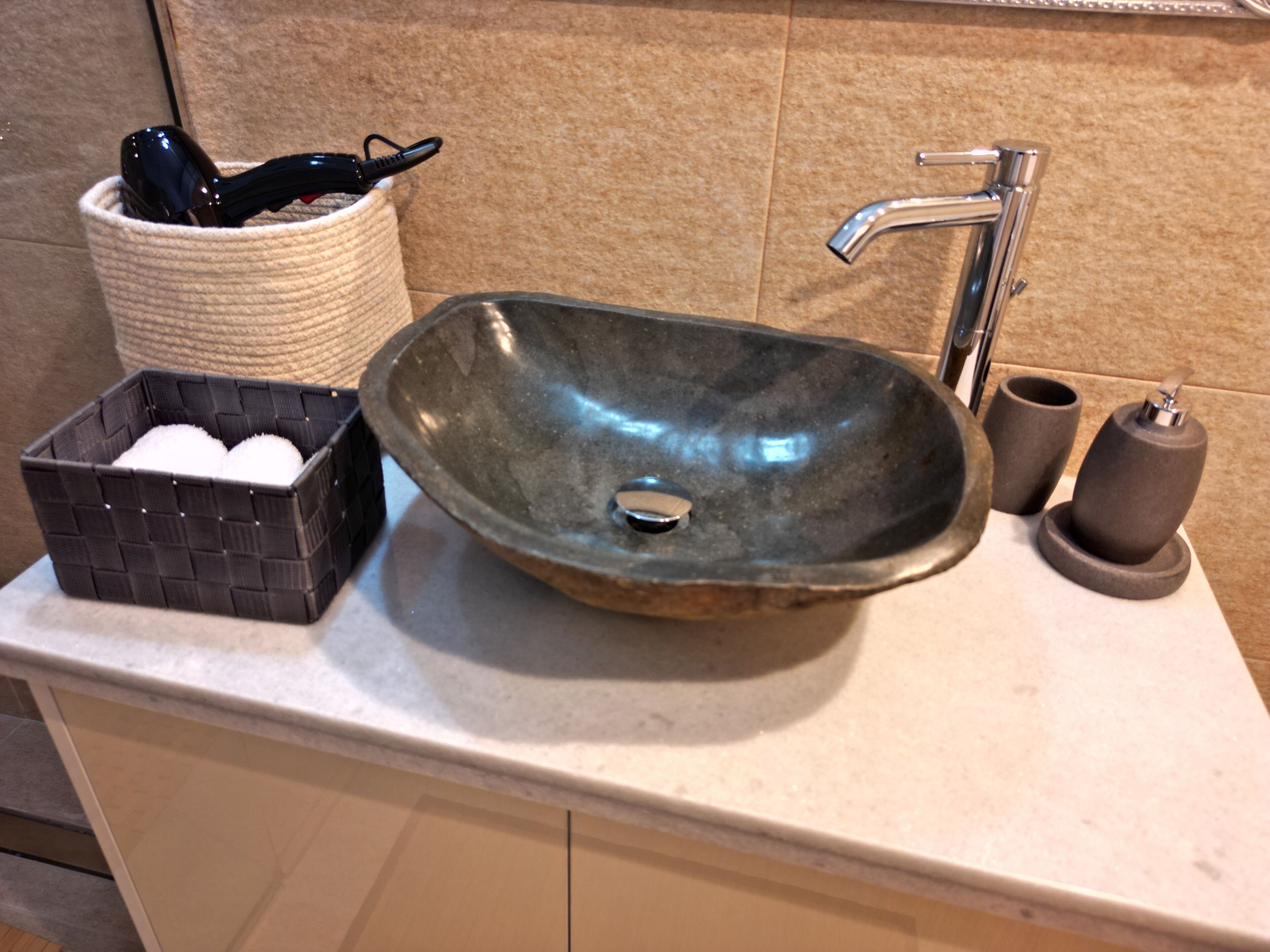 Ein Waschtisch mit modernem Wasserhahn, eine Seifenschale und ein Behälter mit Zahnbürste und Rasierer.