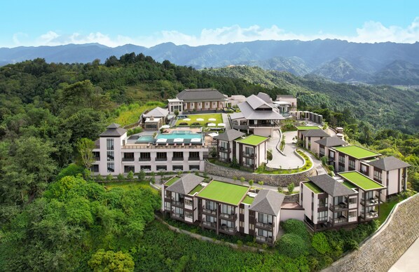 A modern resort with multiple buildings, a swimming pool, and lush greenery. - Dusit Thani Himalayan Resort Dhulikhel Nepal (Shankhu Patichaur)