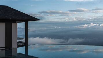 Una piscina infinita con vistas a nubes y montañas.