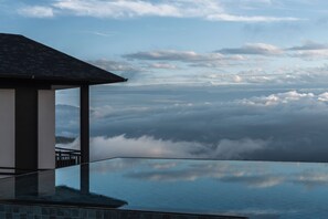 An infinity pool with a view of clouds and mountains.