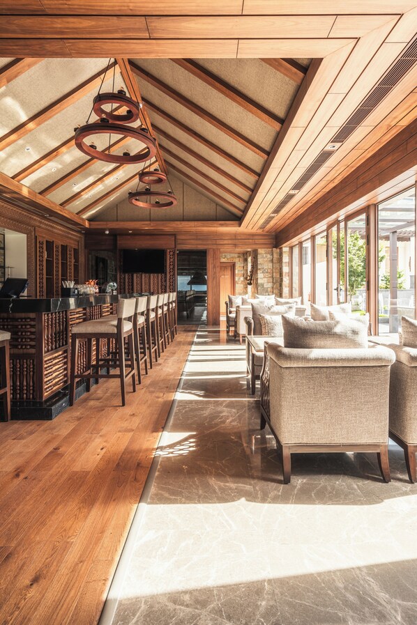 A spacious bar area with wooden flooring, a long counter, and several cushioned seating areas. - Dusit Thani Himalayan Resort Dhulikhel Nepal (Dhulikhel)