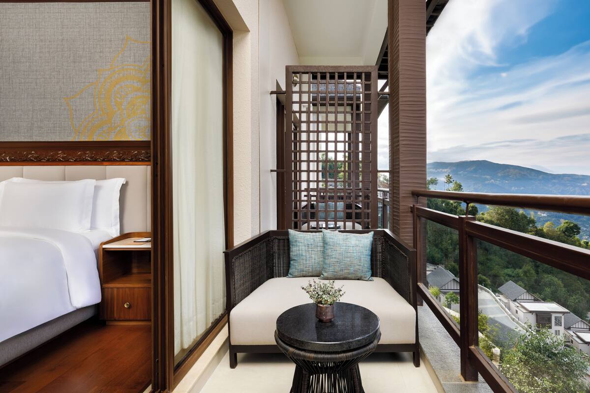 A balcony with a bed, a sofa, and a small table with a plant.