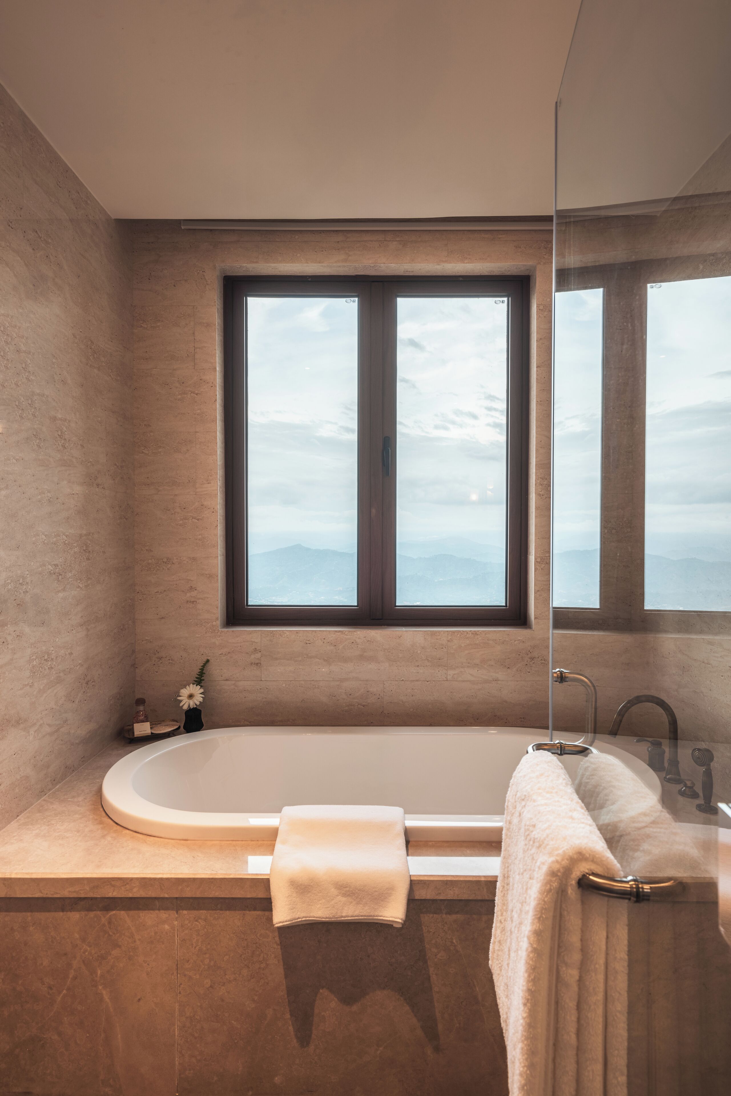 Une salle de bain moderne avec une grande baignoire, une fenêtre donnant sur les montagnes et un miroir.