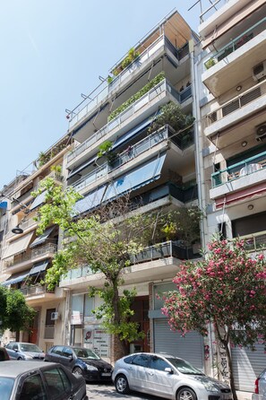 A multi-story residential building with balconies, some with plants. There are parked cars in front. - Modern Equipped Studio w View in Kipseli (Athens)