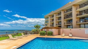 Ein Hotel mit Swimmingpool, Sitzgelegenheiten im Freien und Meerblick.