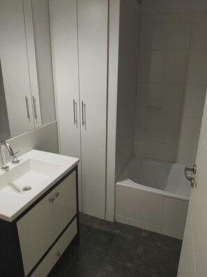A bathroom with a white sink, dark floor tiles, and a bathtub. - Departamento Nuevo Ideal Familia, Mendoza, a Minutos del Centro (Godoy cruz)