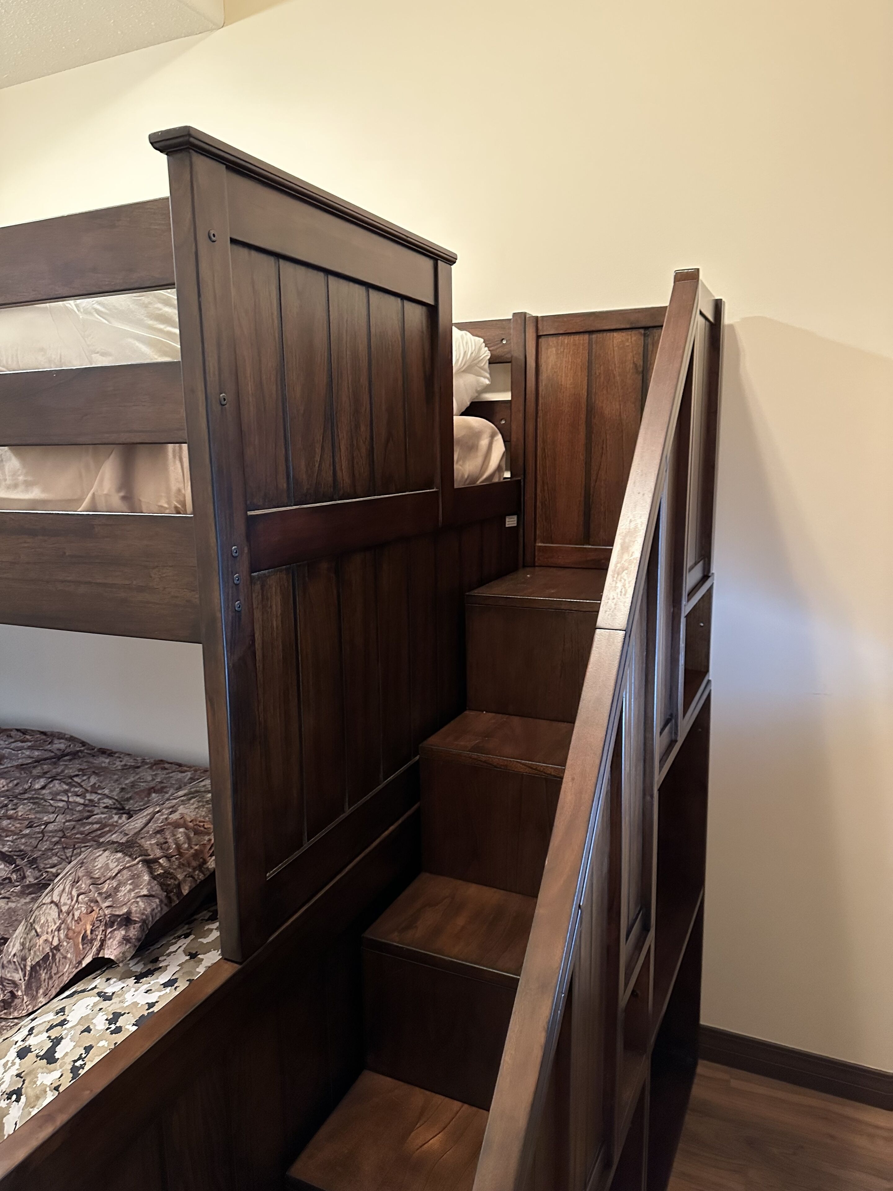 Un letto a castello con struttura in legno e una piccola scala che conduce ad una zona soppalco.