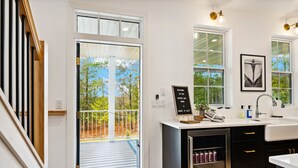 Een moderne keuken met een groot eiland, een inbouwoven en een spoelbak. Er hangt een welkomstbord en een lijst aan de muur.