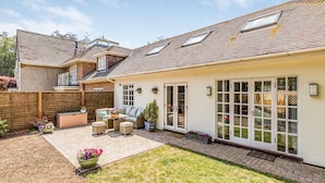 A residential property with a patio area, outdoor seating, and a fenced backyard. - Charming Cottage with Garden - Pass the Keys (Chichester)