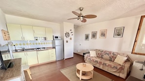 A compact living space with a kitchenette, a ceiling fan, a sofa, and a small round table.