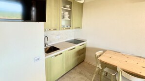 A compact kitchen with a sink, stove, and green cabinets.