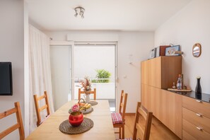 A dining area with a wooden table, chairs, and a view of the outdoors through a sliding door.