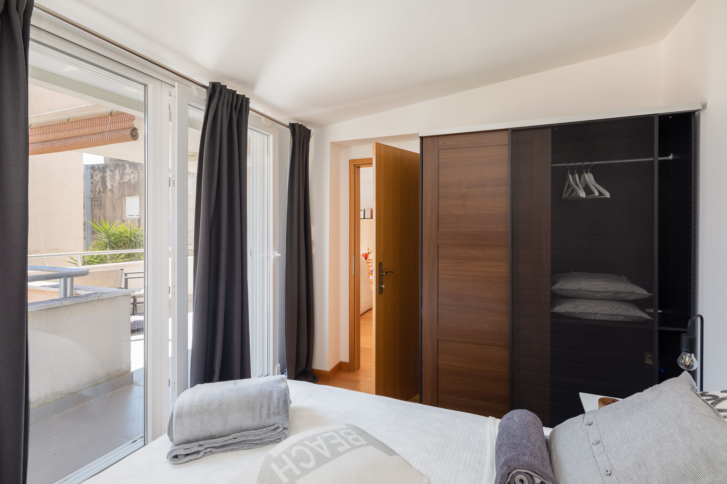A hotel room with a bed, a wardrobe, a bathroom, and a balcony.