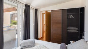 Een hotelkamer met een bed, een kledingkast, een schuifdeur naar een balkon en uitzicht.