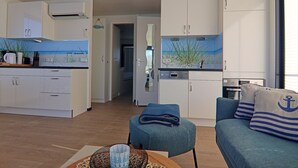 A compact living space with a kitchenette, a dining area, and a seating area with nautical-themed cushions.