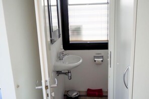 Une petite salle de bain avec un lavabo blanc, un miroir et des toilettes.