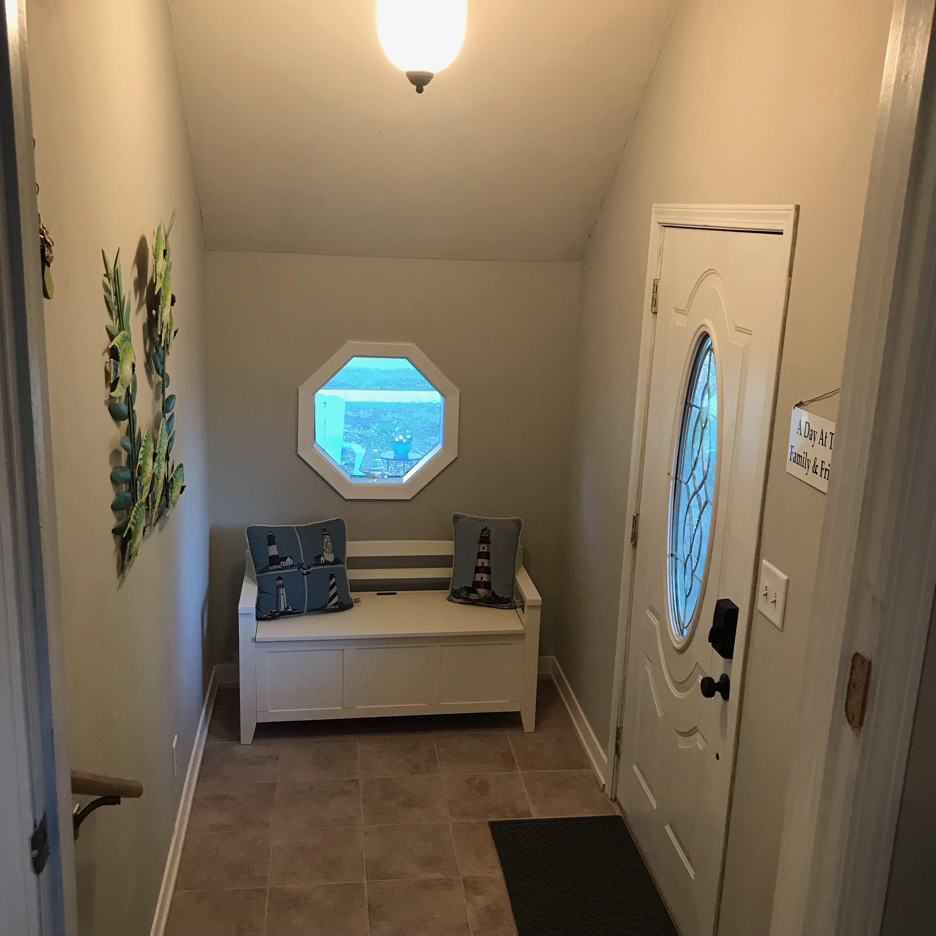 A hallway with a bench, a window, and a door.