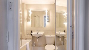 A modern bathroom with two sinks, a toilet, a bathtub, and a large mirror with lights. - The Holland Park Crib - Classy 2bdr House (London)