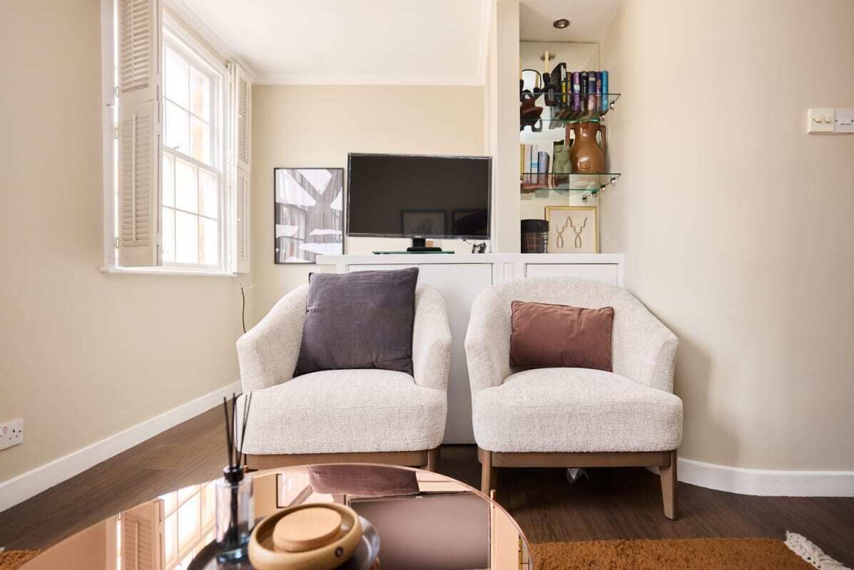 A living room with two armchairs, a coffee table, and a TV on a stand.