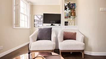 A living room with two armchairs, a coffee table, and a TV on a stand.