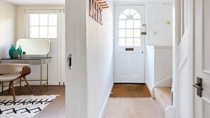A hallway with a white door, a staircase, and a table with chairs. - The Holland Park Crib - Classy 2bdr House (London)