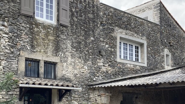 A stone building with a patio area featuring outdoor seating and potted plants. - Stylish duplex on an award-winning vineyard; shared pool; close to the Cevennes (Brissac)