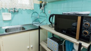 A kitchen with teal tiles, a sink, a kettle, a toaster, and a microwave. - Cozy Cute apt next to Agios Nikolaos (Athens)