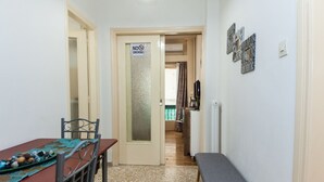 A hallway with a dining table, chairs, a bench, and a 'No Smoking' sign. - Cozy Cute apt next to Agios Nikolaos (Athens)