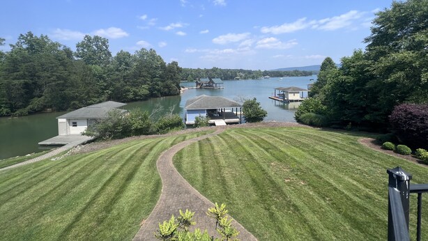 Une propriété au bord du lac, dotée d’une pelouse bien entretenue, d’un quai et d’une petite maison, avec un bateau amarré à proximité.