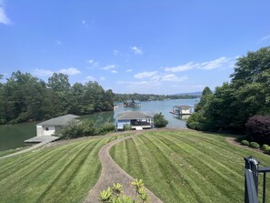 A lakeside property with a well-maintained lawn, dock, and small house with a boat docked nearby.