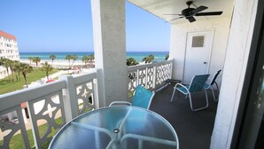 A balcony with a glass table and chairs, overlooking a beach and ocean. - 444 El Matador Condo by RedAwning (Fort Walton Beach)