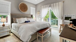 Une chambre à coucher avec un lit, un banc, un bureau, une télévision et une vue sur l’extérieur.