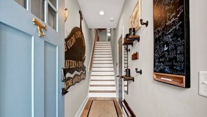 Un couloir avec un escalier menant au deuxième étage, une enseigne sur laquelle on peut lire « Bienvenue à la Cape Town Inn », et un tableau noir avec des inscriptions.